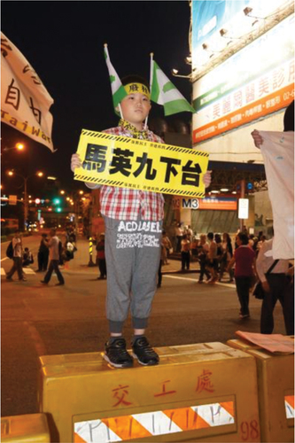 Figure 4. Ten-year old boy standing on the street holding a signboard to ask the president to stand down.