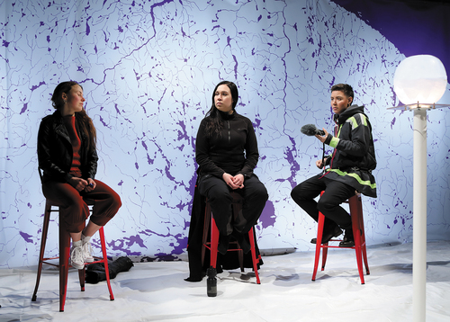 Image 1. Sitting in front of a stylized map of Sápmi, Mio Negga (right) acts as a facilitator for the witness testimonies offered by Elina Israelsson (centre) and Sarakka Gaup (left), Photograph by Ilkka Volanen. © Giron Sámi Teáhter.