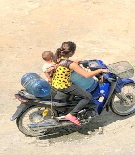 Figure 4. Mother on motorbike with baby in the sling fetching water. Source: Author’s own photograph.