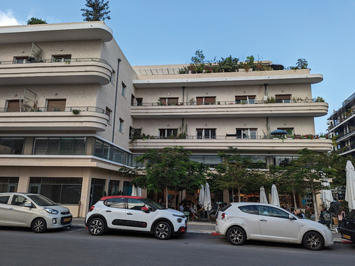 Figure 6. The Vilozny House (constructed in 1936–7 on Mikvei Israel Street, Tel Aviv) was designed by architect Mordechai Rosengarten. Over time the building deteriorated and many of its residential flats were converted into office and warehouse spaces. Its front court was converted into a parking lot, serving a garage located on the entrance floor of the building. Due to its historical and architectural values, the conservation plan listed it as a heritage building with strict restrictions. Thus, the owners could initiate a transfer of development rights (TDR) as part of its conservation. In 2012 two developers struck a deal, and a year later, the obligatory statutory plan was approved, transferring 886 square meters of unrealized development rights to a new residential building in Yehuda Ha-Levi Street. The building currently incorporates thirty small apartments, two penthouses, and a bustling coffee shop that is frequented by many locals. (photo taken by authors).