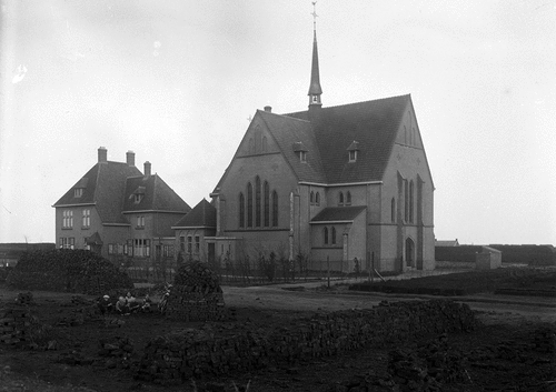Figure 5. St Antony’s church with rectory (built in 1921). In the foreground the former edge of the Bargerveen where turves are being dried. Later these buildings were designated as national monuments partly because of their special location on the edge of the peat-colonial village of Zwartemeer and close to the present-day Bargerveen nature reserve. Photo: J.B. Schröer, Drents Archief (collectie Schröer).