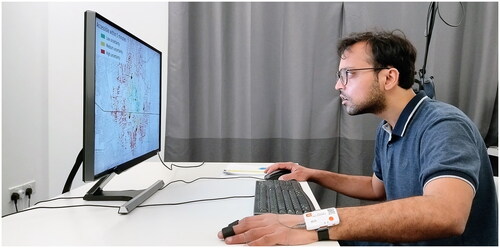 Figure 2. Experimental setup: The eye tracker is mounted at the bottom of the screen, and the participant is wearing the Shimmer GSR sensor on his left wrist.