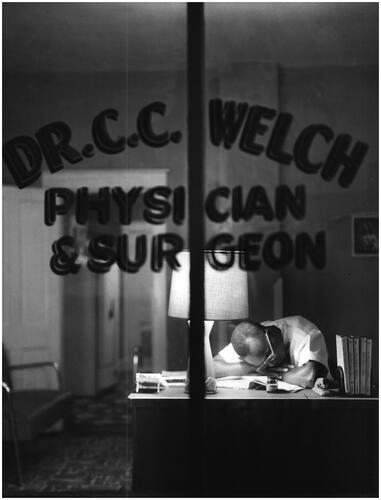 Figure 4 Unknown photographer, ‘The life of a young doctor is arduous. Here, after a long and tiring day, Dr Welch naps at his office desk’. ‘A Doctor Makes His Rounds’, 1958. USIA ‘Picture Story’ Photographs, 1955–84, Record Group 306. 306-ST-460-57-24393.